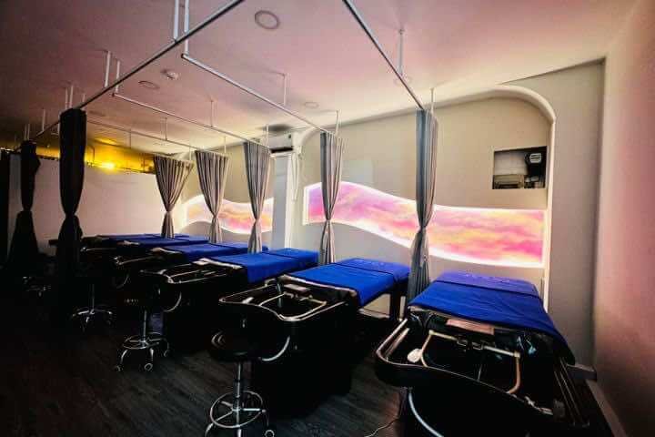 Hàng ghế nằm với nệm xanh trong một phòng có ánh sáng dịu và rèm ngăn cách giữa các ghế.
