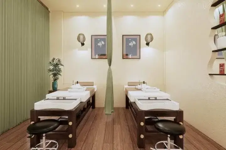 Phòng spa với hai giường massage, trang trí nhẹ nhàng, có tranh treo tường và bình cây cảnh bên cạnh.