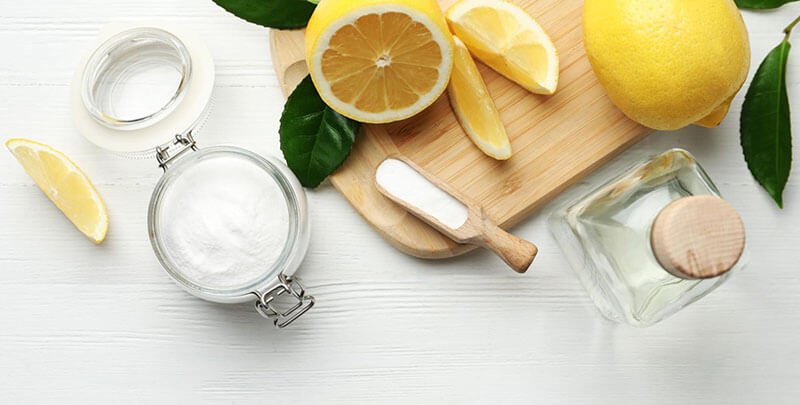 Chanh, muối và lọ thủy tinh trên bàn gỗ trắng, chụp từ trên cao.