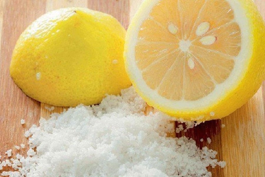 Nửa quả chanh và muối trên mặt thớt gỗ.