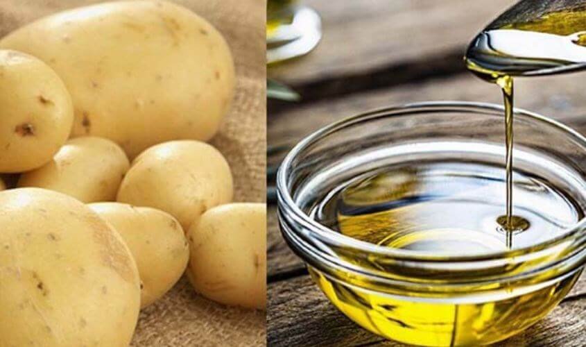 Khoai tây và một bát nhỏ đựng dầu ăn đang được rót vào, trên nền gỗ.