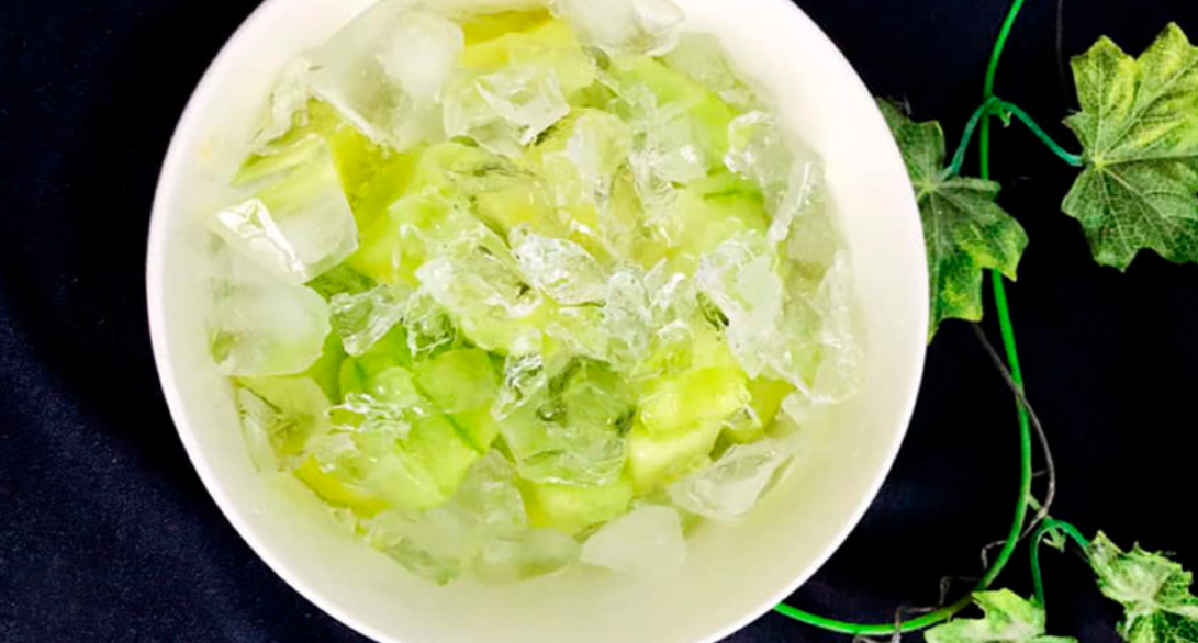 Bát đựng khúc bạch và đá lạnh, bên cạnh có lá xanh trang trí trên nền đen.