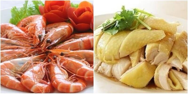 Đĩa tôm luộc và gà luộc bày trí đẹp mắt trên bàn, kèm rau sống và trang trí hoa cà chua.