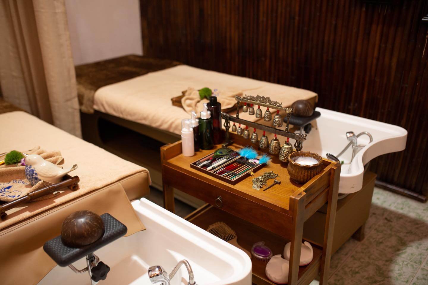 Phòng spa với giường massage, bồn rửa chân và bàn nhỏ chứa các dụng cụ chăm sóc, chai lọ và trang trí.