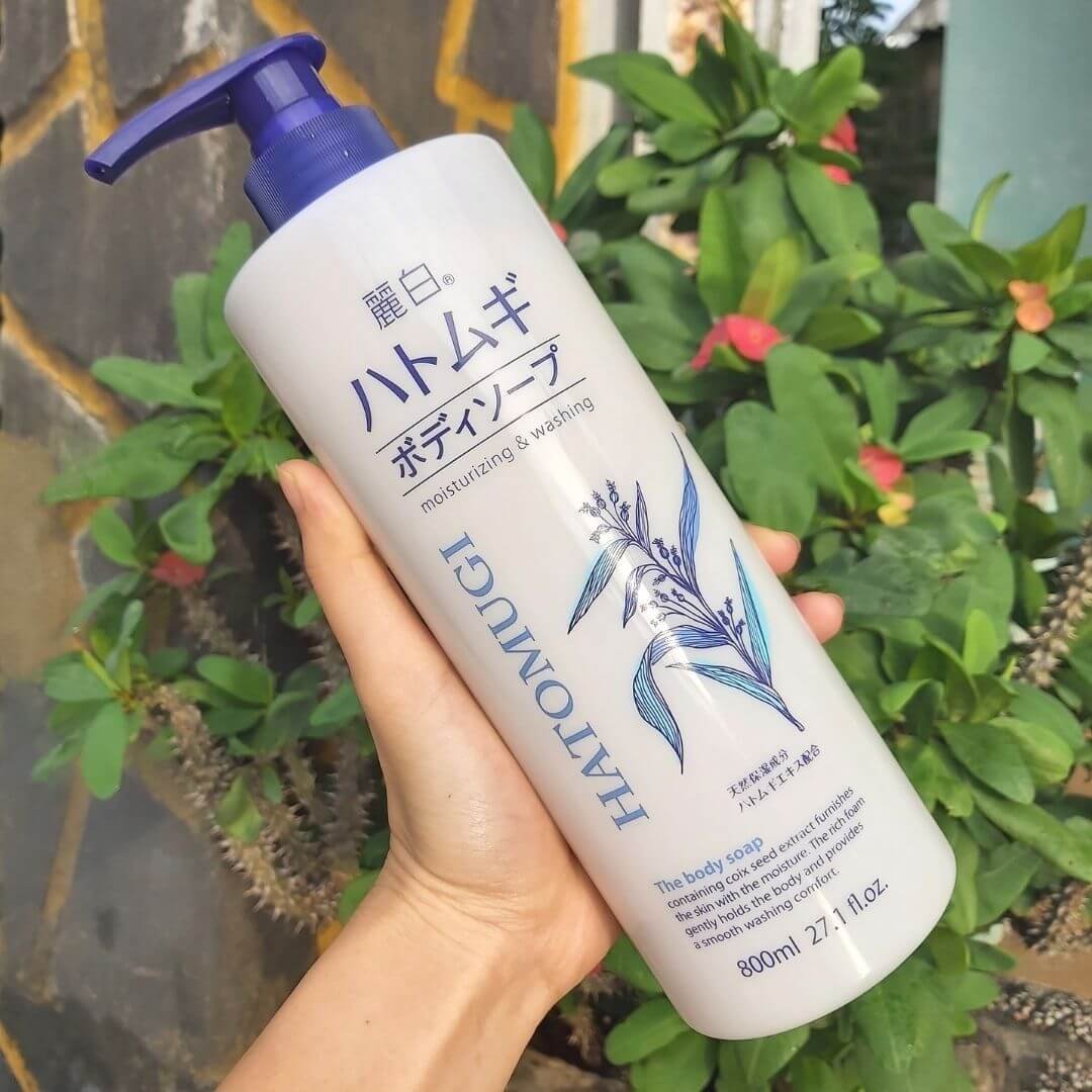 Chai sữa tắm Hatomugi 800ml với thiết kế nắp bơm, cầm trên tay, nền là cây xanh.