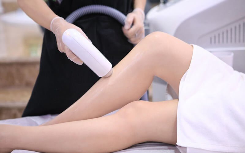 Người đang thực hiện liệu trình triệt lông bằng thiết bị chuyên dụng trên chân trong một cơ sở thẩm mỹ.