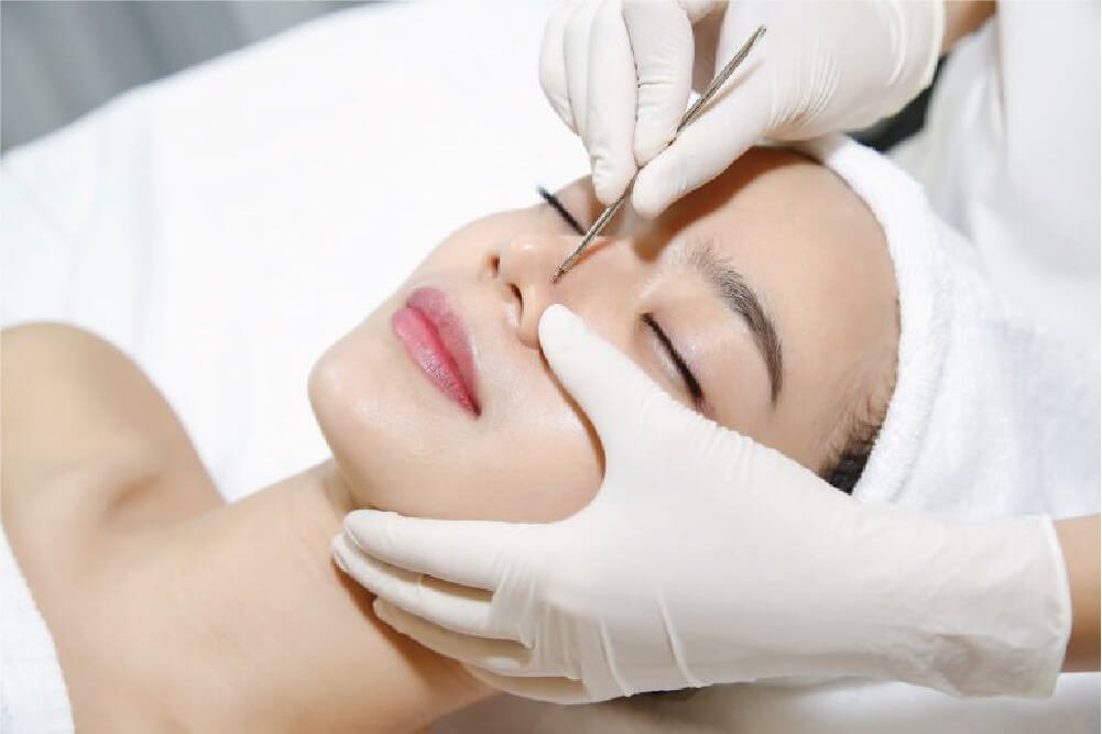 Người đang được chăm sóc da mặt, tay đeo găng đang thực hiện liệu trình làm đẹp trên mũi.