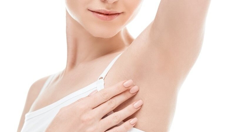 Người mặc áo trắng chạm vào vùng da dưới cánh tay, thể hiện sự chăm sóc cơ thể.