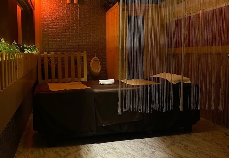 Phòng spa với giường massage, rèm dây và ánh sáng dịu nhẹ, tạo không gian thư giãn và yên tĩnh.