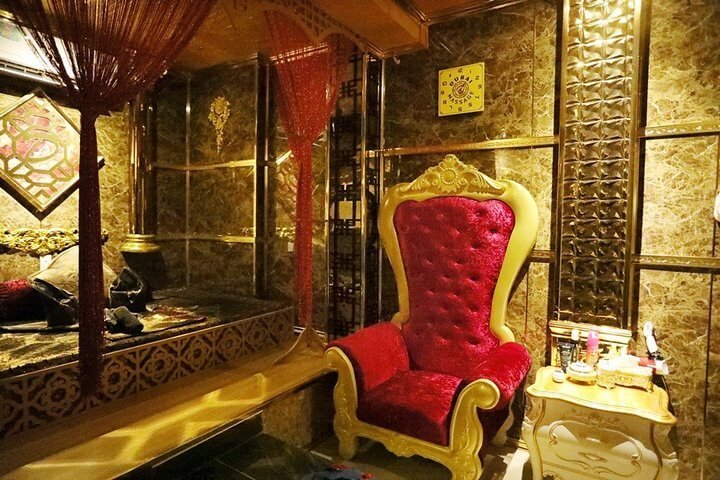 Ghế bành sang trọng màu đỏ trong phòng trang trí hoàng gia với tường và nội thất lộng lẫy.