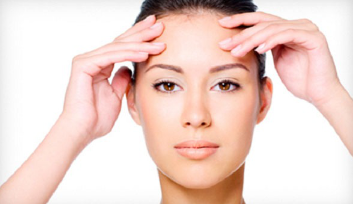 Người phụ nữ đặt hai tay lên trán trên nền trắng, thể hiện sự thư giãn và chăm sóc bản thân.