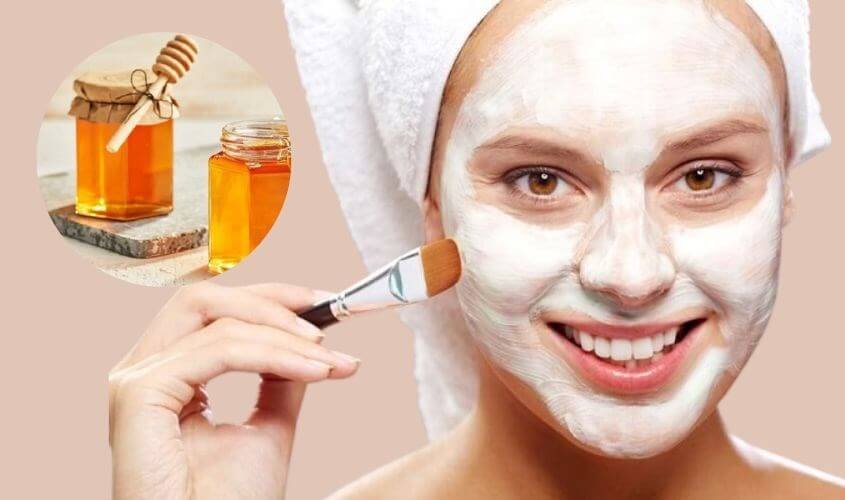 Người đắp mặt nạ dưỡng da, cầm cọ, nền có hình ảnh mật ong trong lọ thủy tinh.