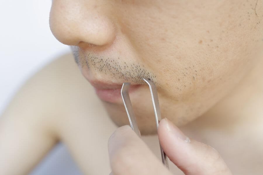 Người đang dùng nhíp nhổ râu trên môi, cận cảnh khuôn mặt và tay, không nhìn thấy danh tính.