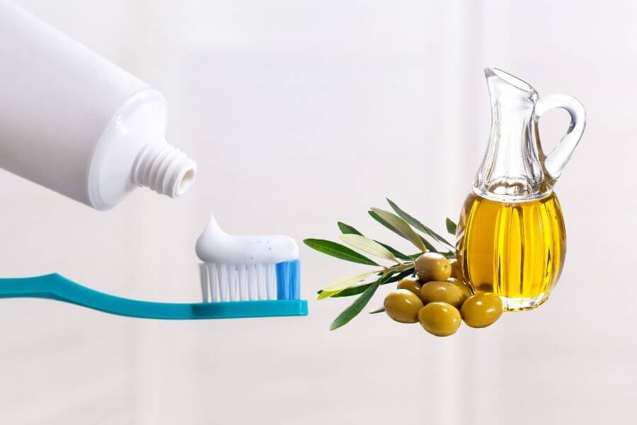 Bàn chải đánh răng với kem, bên cạnh là chai dầu ô liu và vài quả ô liu, biểu tượng của tự nhiên và vệ sinh.