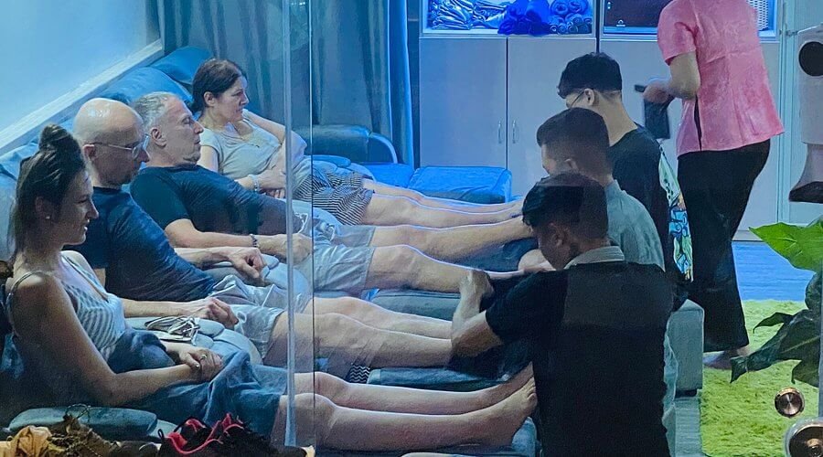 Nhóm người ngồi trên ghế, được massage chân bởi nhân viên trong một không gian thư giãn trong nhà.