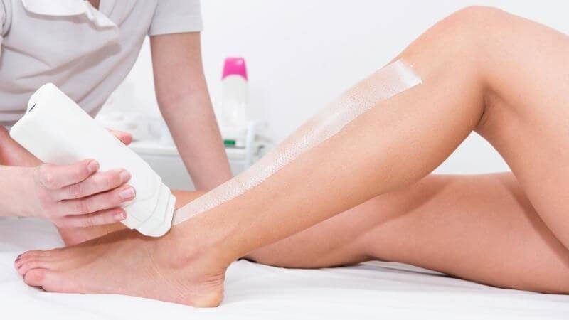 Người đang bôi kem lên chân một người khác trong không gian chăm sóc da chuyên nghiệp.