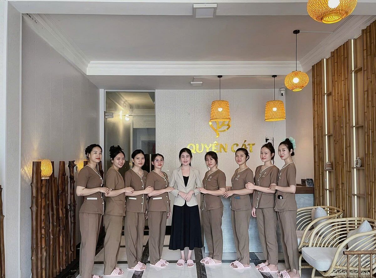 Nhóm nhân viên đứng xếp hàng trong một không gian nội thất với ánh sáng ấm áp và trang trí tre.