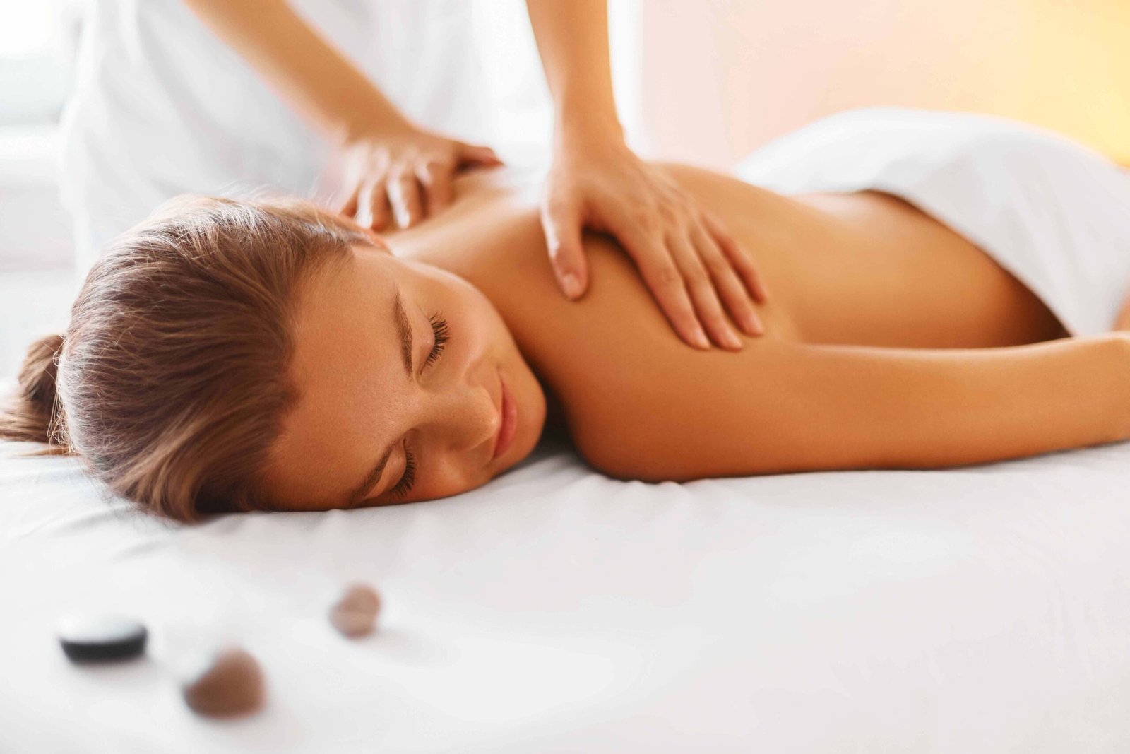 Người đang nằm thư giãn trên giường massage, được xoa bóp vai, không gian thư giãn.