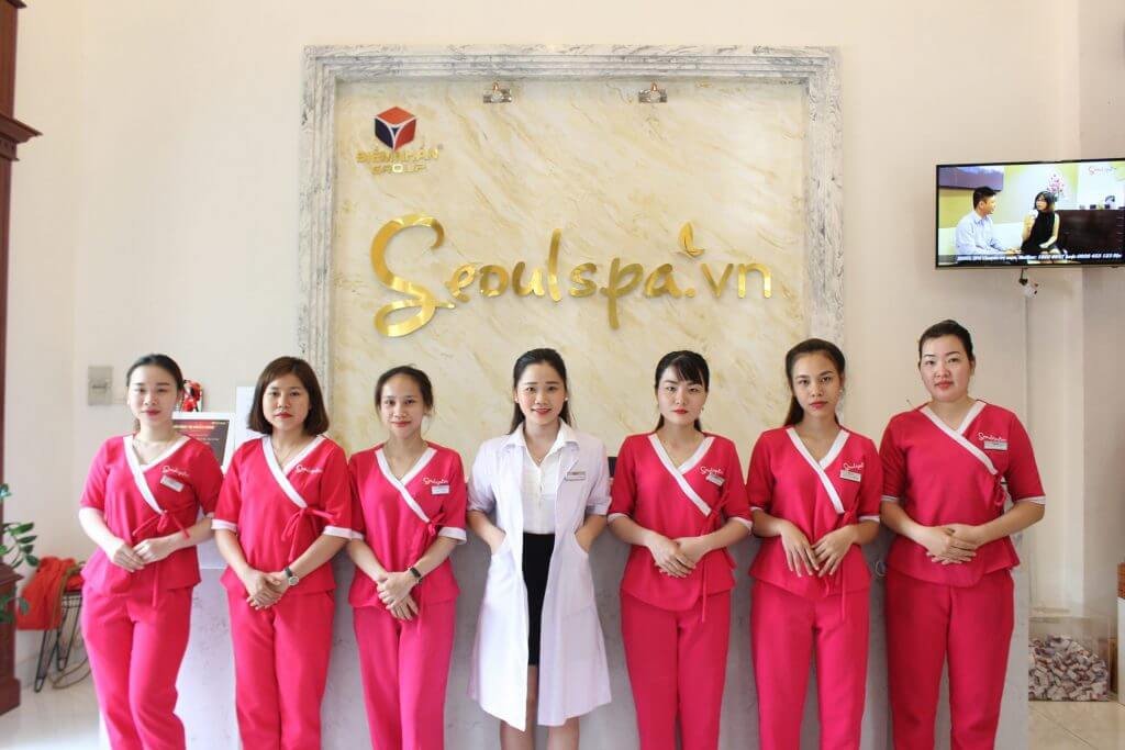 Nhóm người mặc đồng phục spa đứng trước biển hiệu "Seoulspa.vn" trong một không gian nội thất.