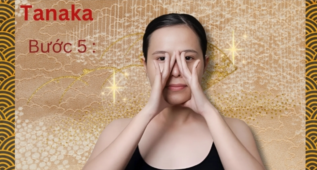 Người phụ nữ thực hiện động tác massage khuôn mặt theo phương pháp Tanaka trên nền họa tiết truyền thống.