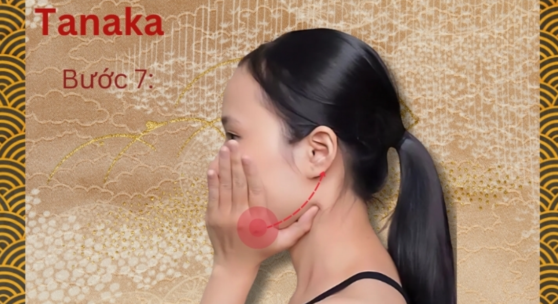Người đang thực hiện động tác massage mặt theo hướng dẫn với nền hoa văn truyền thống.