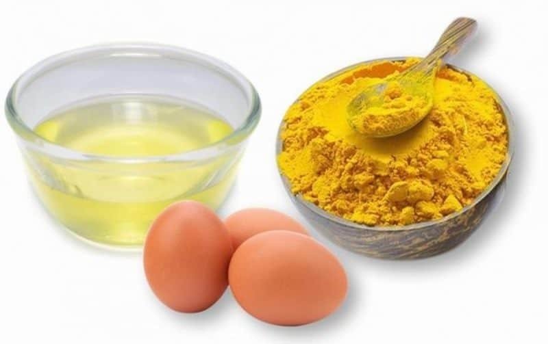 Bát lòng trắng trứng, hai quả trứng và bột nghệ trong bát cùng chiếc thìa nhỏ đặt bên cạnh.