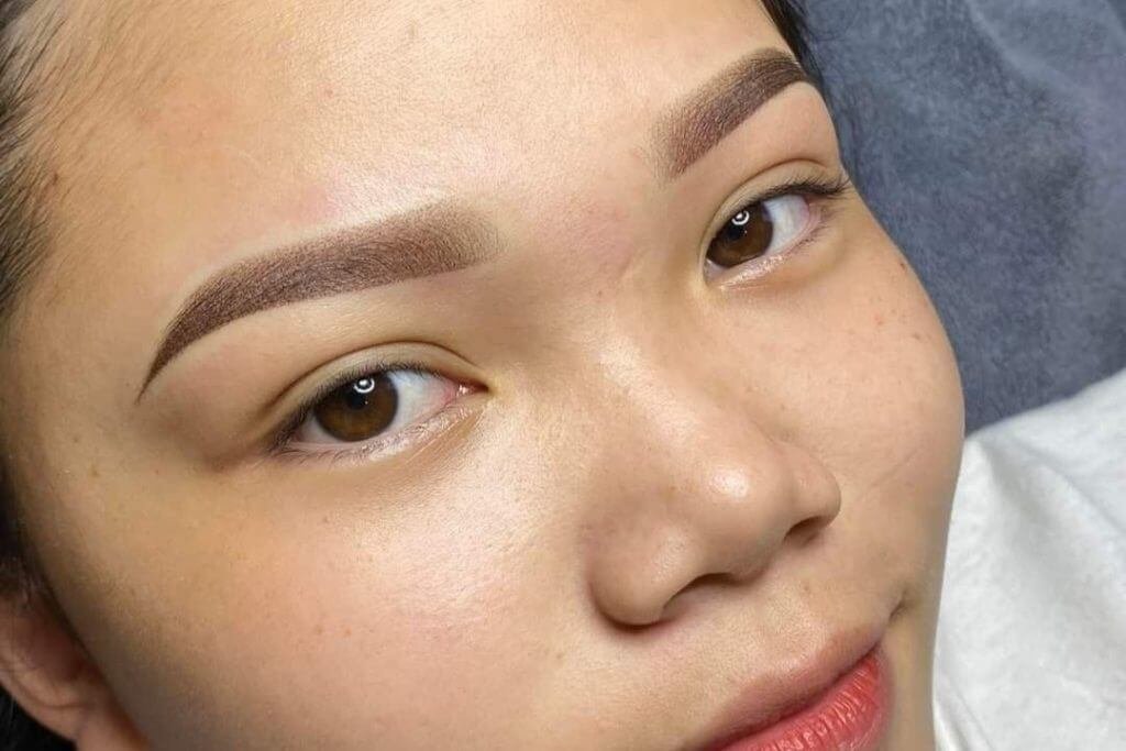 Cận cảnh khuôn mặt với lông mày được trang điểm kỹ lưỡng, làn da mịn màng và đôi môi nhẹ nhàng.