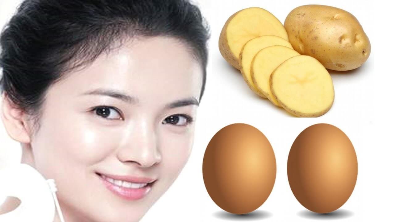 Người phụ nữ tươi cười bên cạnh khoai tây và trứng gà trên nền trắng.