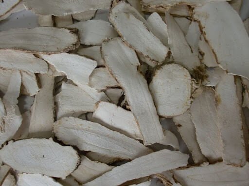 Các lát cắt mỏng của một loại củ màu trắng, sắp xếp lộn xộn, bề mặt có vân nâu nhạt.