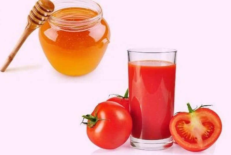 Hũ mật ong, ly nước ép cà chua và hai quả cà chua tươi trên nền trắng.