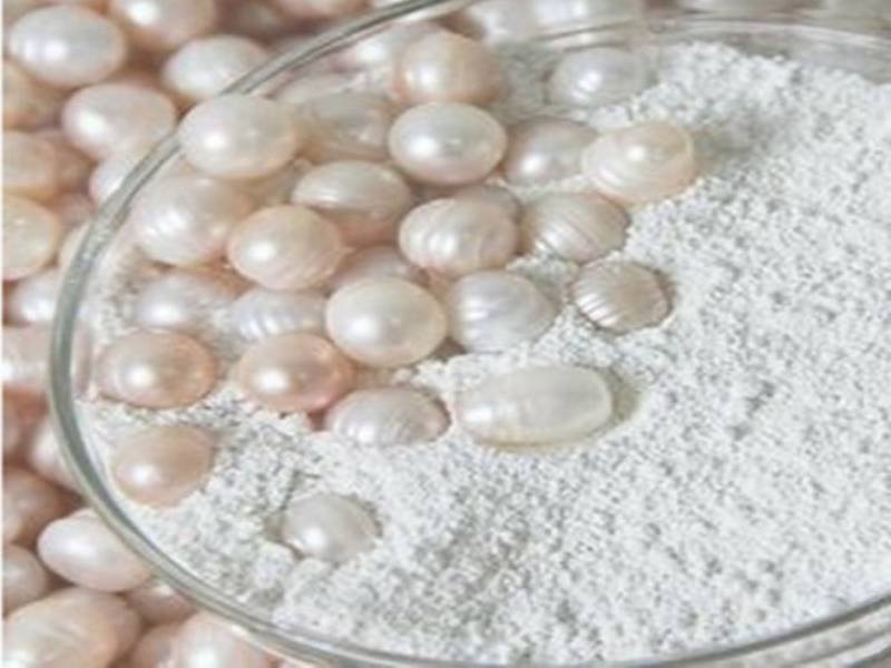 Hình ảnh những viên ngọc trai trắng và hồng nằm trên bột trắng trong một chiếc đĩa thủy tinh.