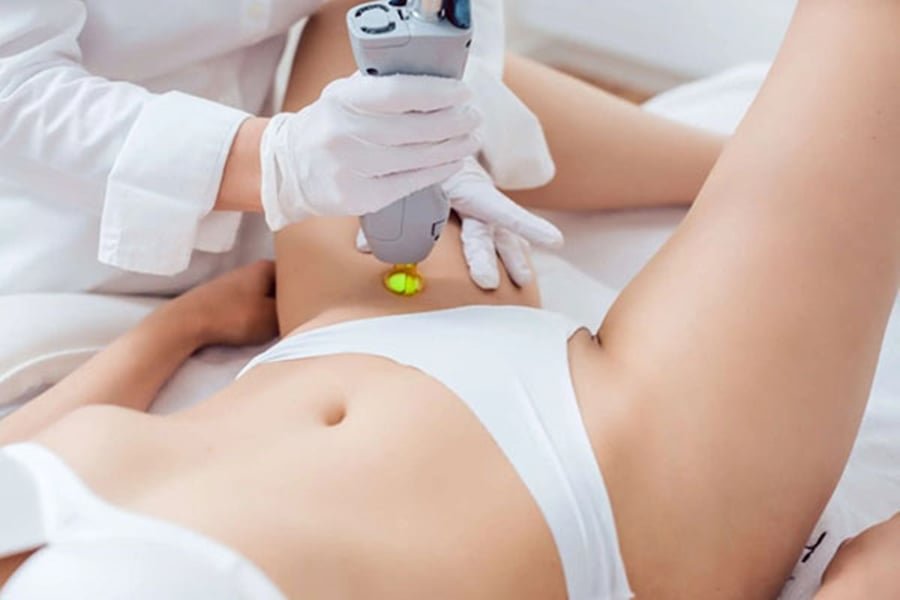 Người mặc đồ bảo hộ thực hiện liệu pháp laser trên vùng da của khách hàng mặc đồ trắng.