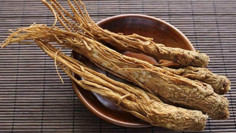 Rễ cây khô đặt trong bát gỗ trên nền tre, thể hiện chi tiết và kết cấu tự nhiên.