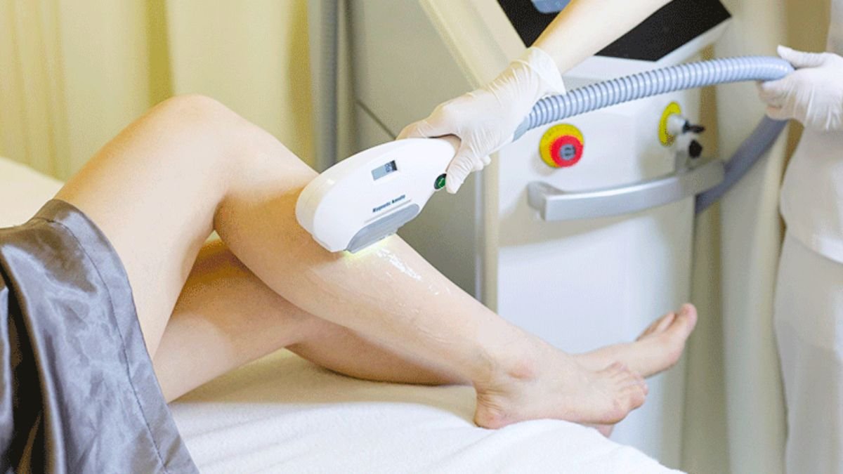 Người đang thực hiện triệt lông bằng thiết bị laser trên chân tại một cơ sở thẩm mỹ.