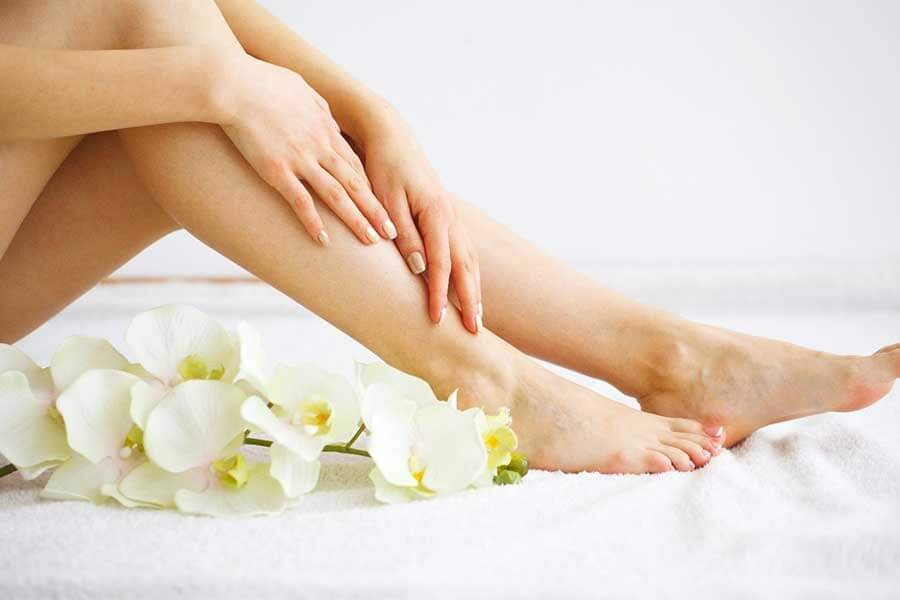 Đôi chân đặt trên khăn trắng với hoa lan trắng trang trí bên cạnh.