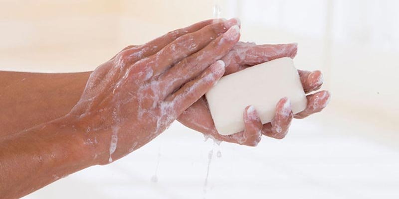 Đôi tay đang rửa với xà phòng dưới vòi nước, tạo nhiều bọt trắng.