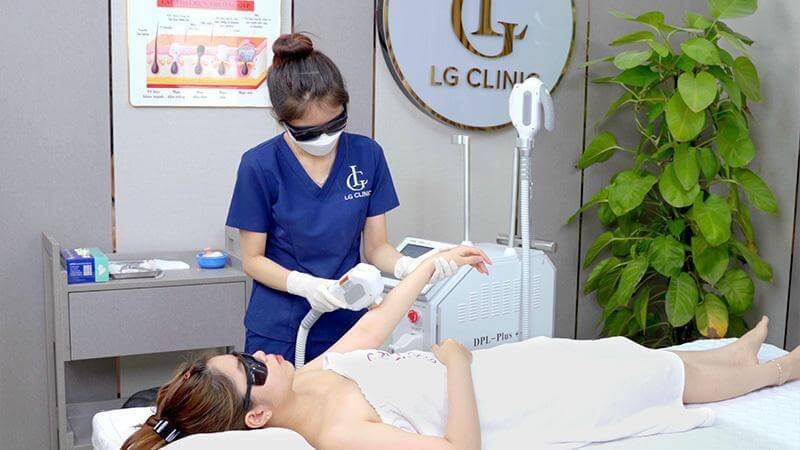 Nhân viên thẩm mỹ thực hiện liệu trình chăm sóc da cho khách hàng tại phòng khám có thiết bị hiện đại.