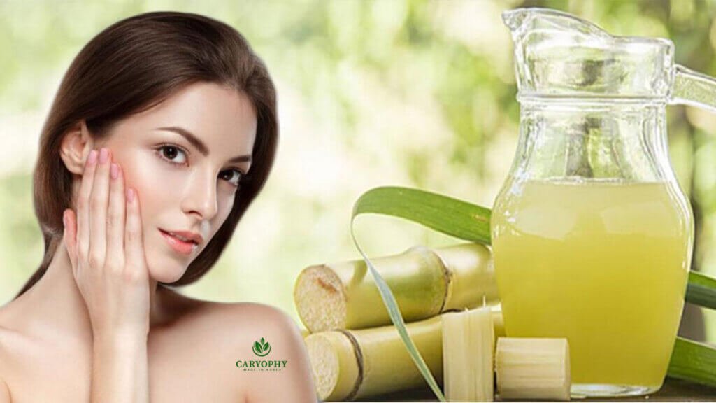 Người phụ nữ chạm vào má, cạnh đó là cốc nước mía và một số khúc mía trên nền xanh mờ.