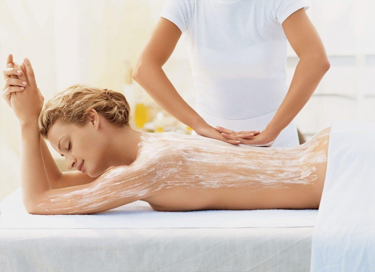 Người đang được massage lưng trong spa, với kem được thoa đều trên da, tạo cảm giác thư giãn.