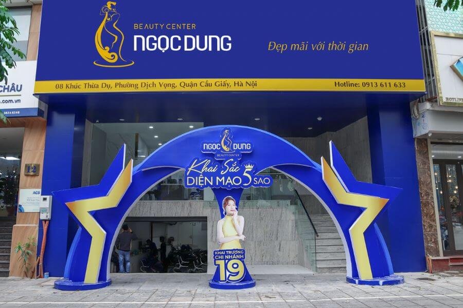 Mặt tiền trung tâm làm đẹp với biển hiệu lớn và cổng chào màu xanh, có biểu tượng ngôi sao vàng.