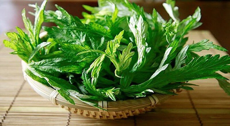 Giỏ tre chứa nhiều lá xanh tươi, đặt trên bề mặt bằng tre.