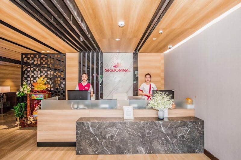 Quầy lễ tân với hai nhân viên đứng phía sau, không gian trang trí hiện đại và lịch sự.