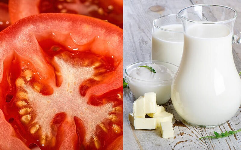 Cận cảnh lát cắt cà chua đỏ và bình sữa, bơ, sữa chua trên bàn gỗ, thể hiện hai loại thực phẩm khác nhau.