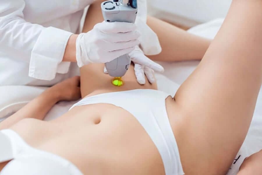 Nhân viên thực hiện liệu pháp laser trên vùng bụng của một người nằm, sử dụng thiết bị cầm tay.