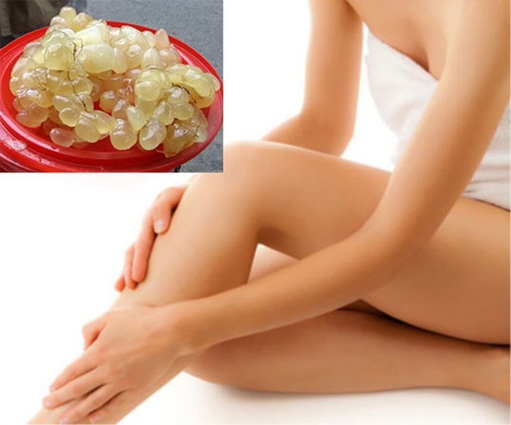 Hình ảnh một người ngồi, tay chạm vào chân, bên cạnh là chậu chứa nhiều hạt màu vàng nhạt.