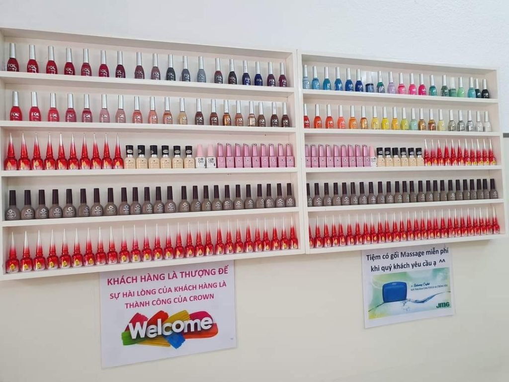 Top 10+ Tiệm Nail Quận 11 Đẹp, Chuyên Nghiệp Được Yêu Thích Hiện Nay 1 Kệ trưng bày nhiều lọ sơn móng tay đủ màu sắc, bên dưới có hai biển hiệu quảng cáo dịch vụ khách hàng.