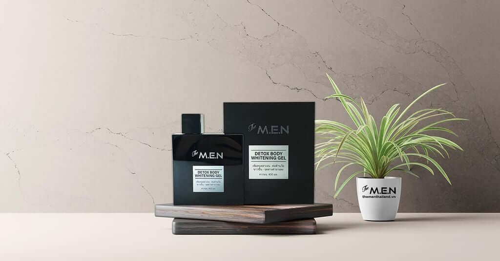 Chai gel dưỡng da màu đen trên kệ gỗ, bên cạnh là chậu cây xanh nhỏ, nền tường màu xám nhạt.