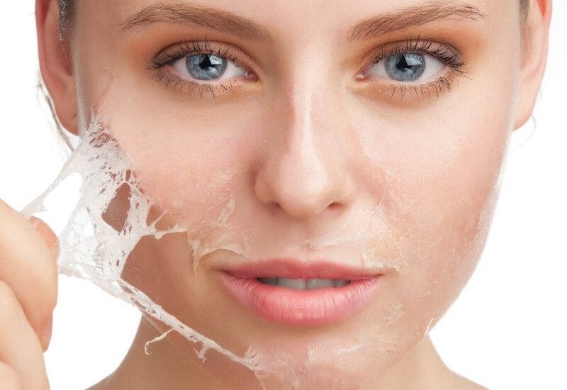 Người đang bóc lớp mặt nạ chăm sóc da trên mặt trong hình cận cảnh.