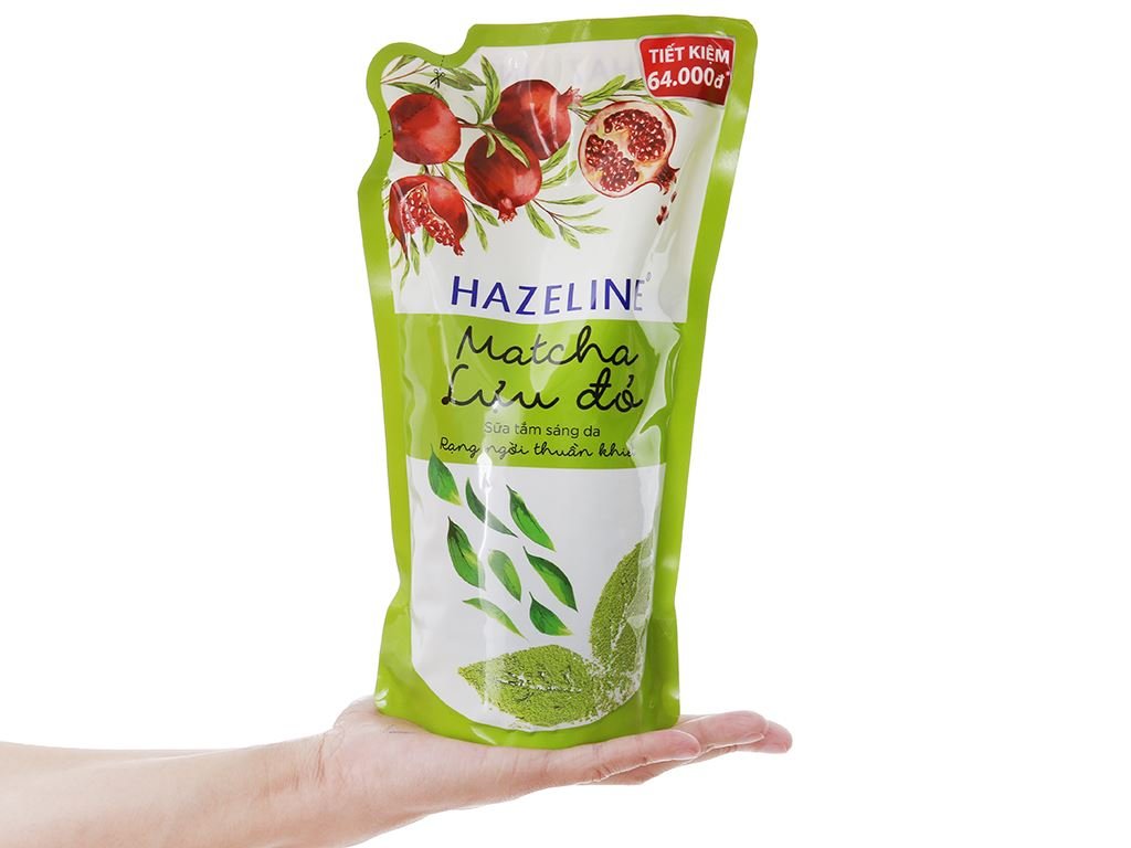 Túi sữa tắm Hazeline Matcha Lựu Đỏ màu xanh, đỏ, nằm trên bàn tay, có hình quả lựu và lá trà.