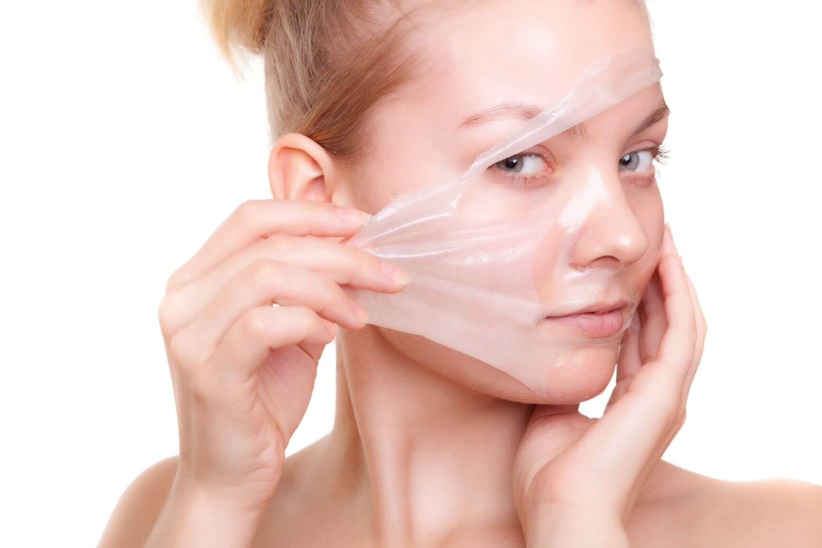 Người đang bóc mặt nạ dưỡng da trong suốt khỏi mặt, biểu cảm chăm chú.